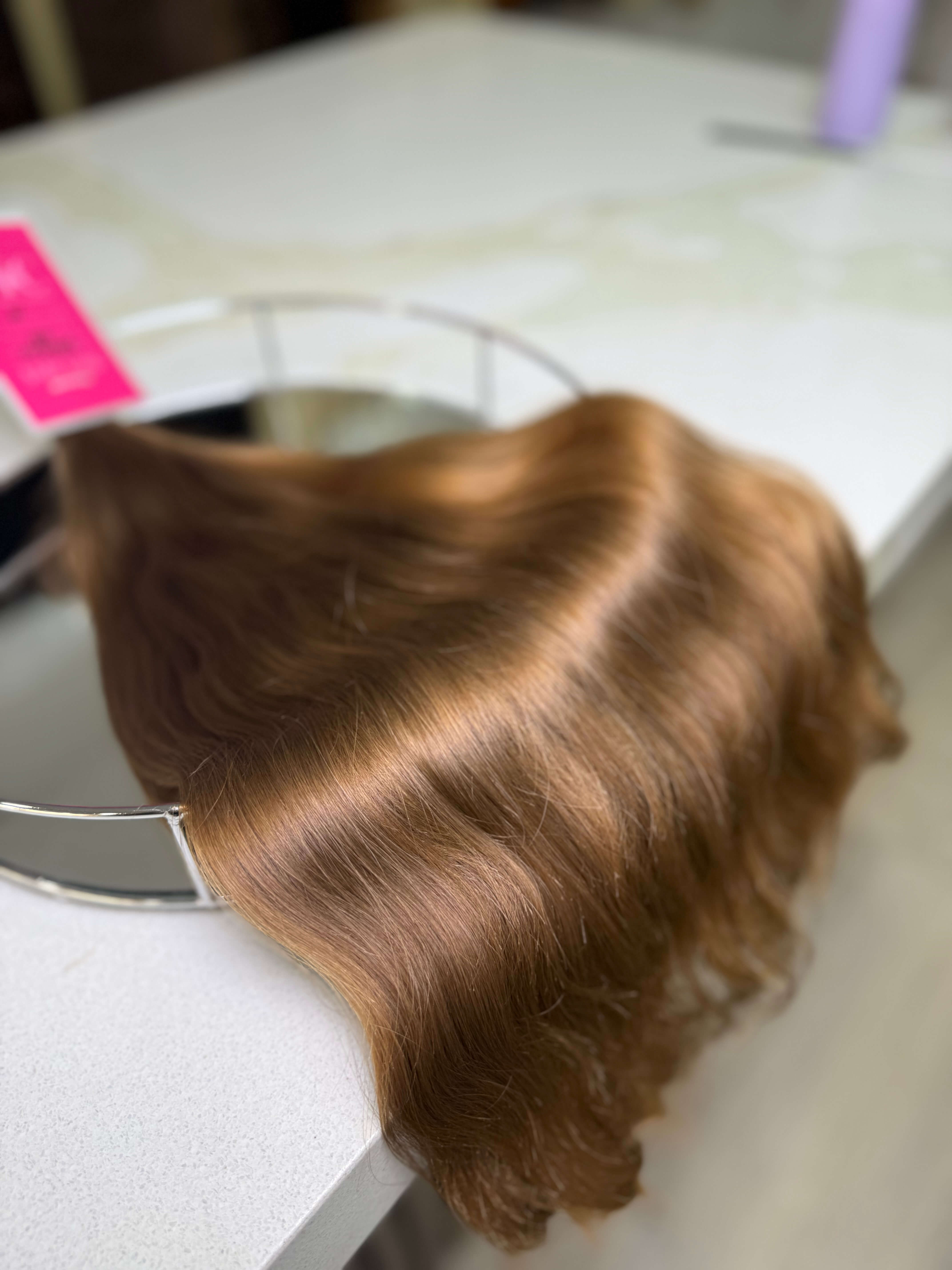 Brown hair extensions on a stand with a blurred background