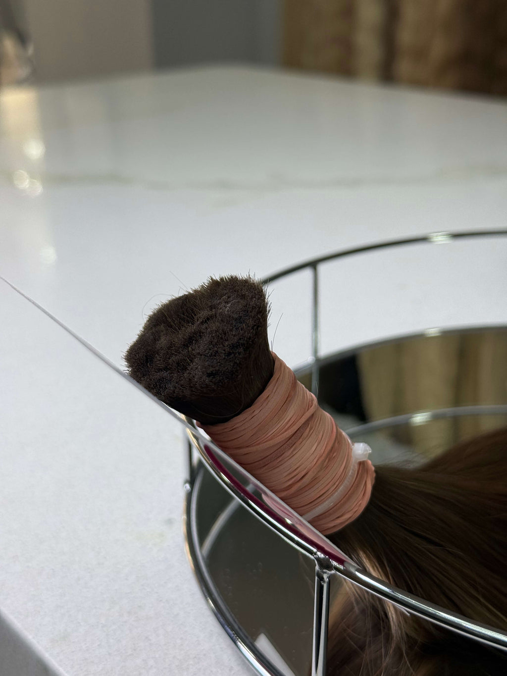 Hairbrush with a hair tie on a white surface