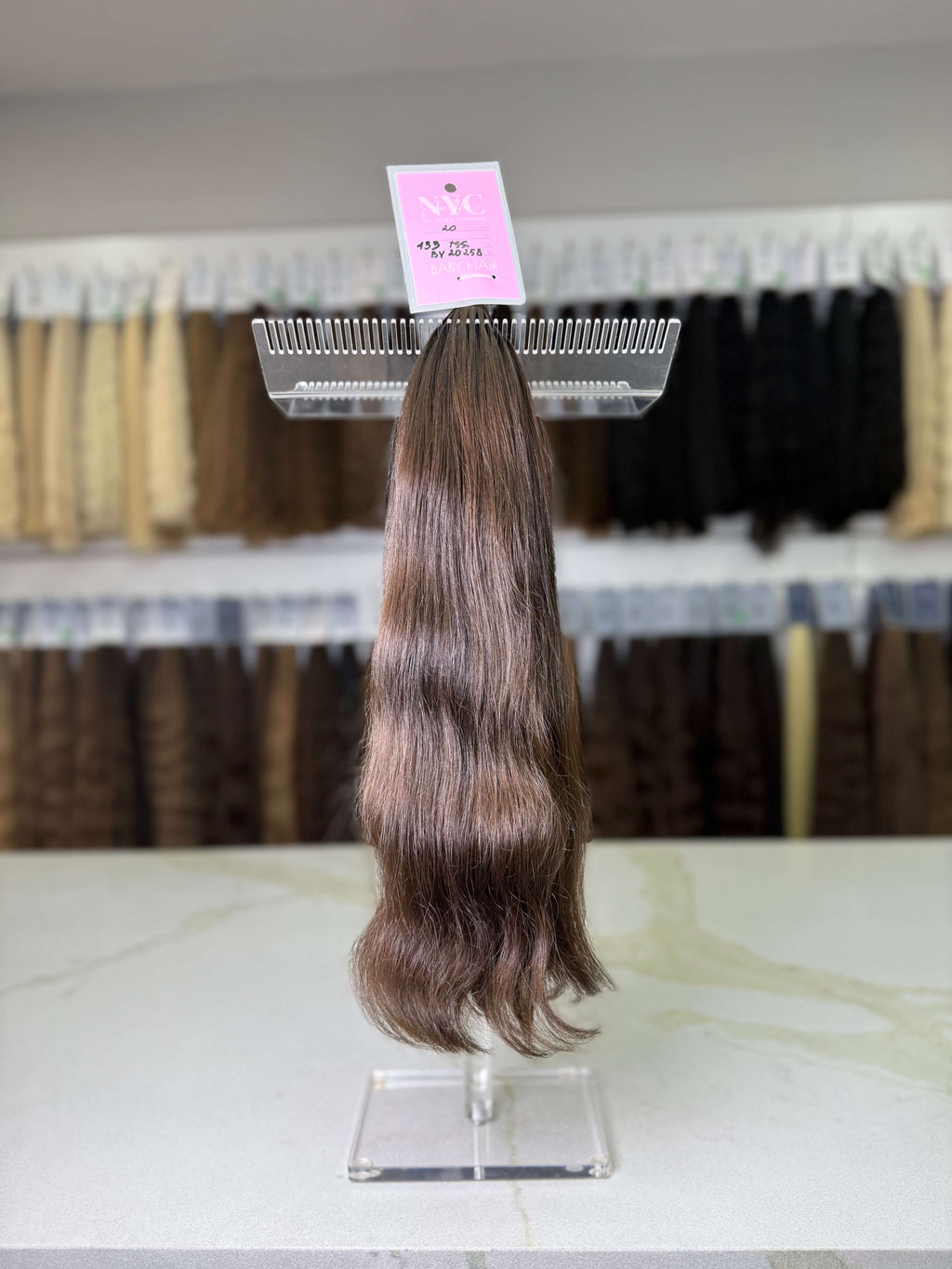 Hair extension on a display stand with a pink label in a store setting.