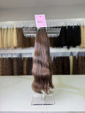 Hair extension on a display stand with a pink label in a store setting.