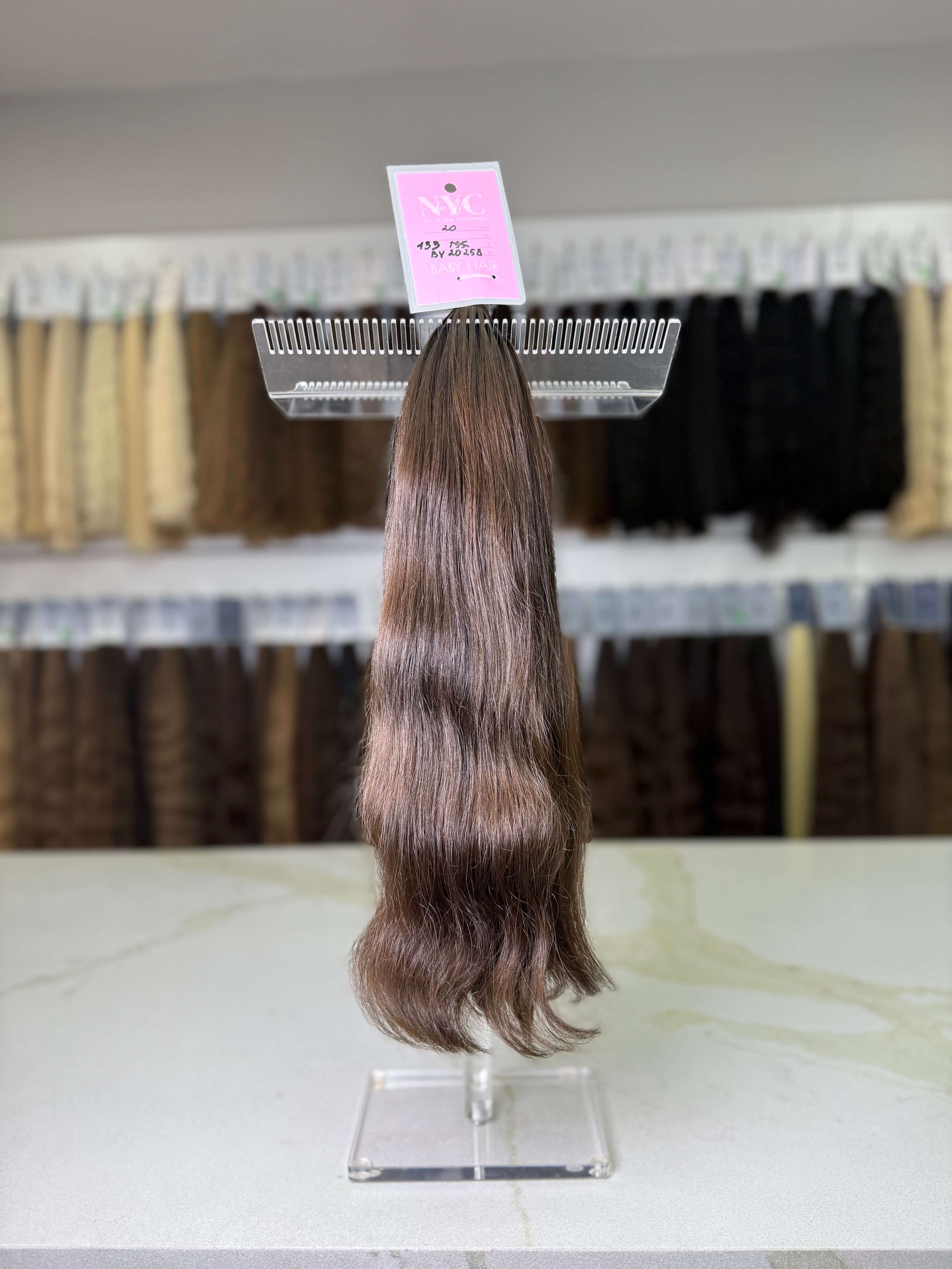 Hair extension on a display stand with a pink label in a store setting.