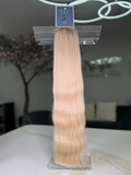 Blonde hair extensions on a comb with a blurred indoor background