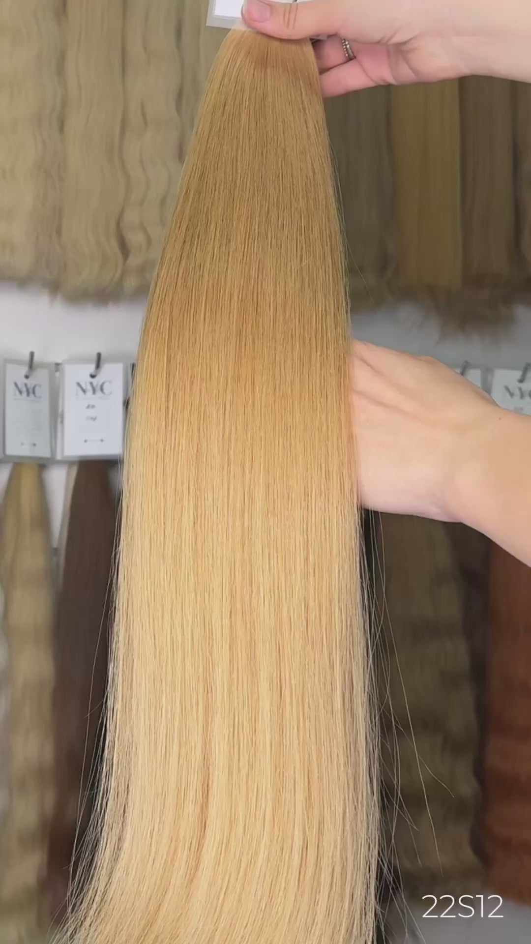 Holding warm blonde straight hair extension in front of full color bar wall, LUXHAIRNYCSHOP NYC