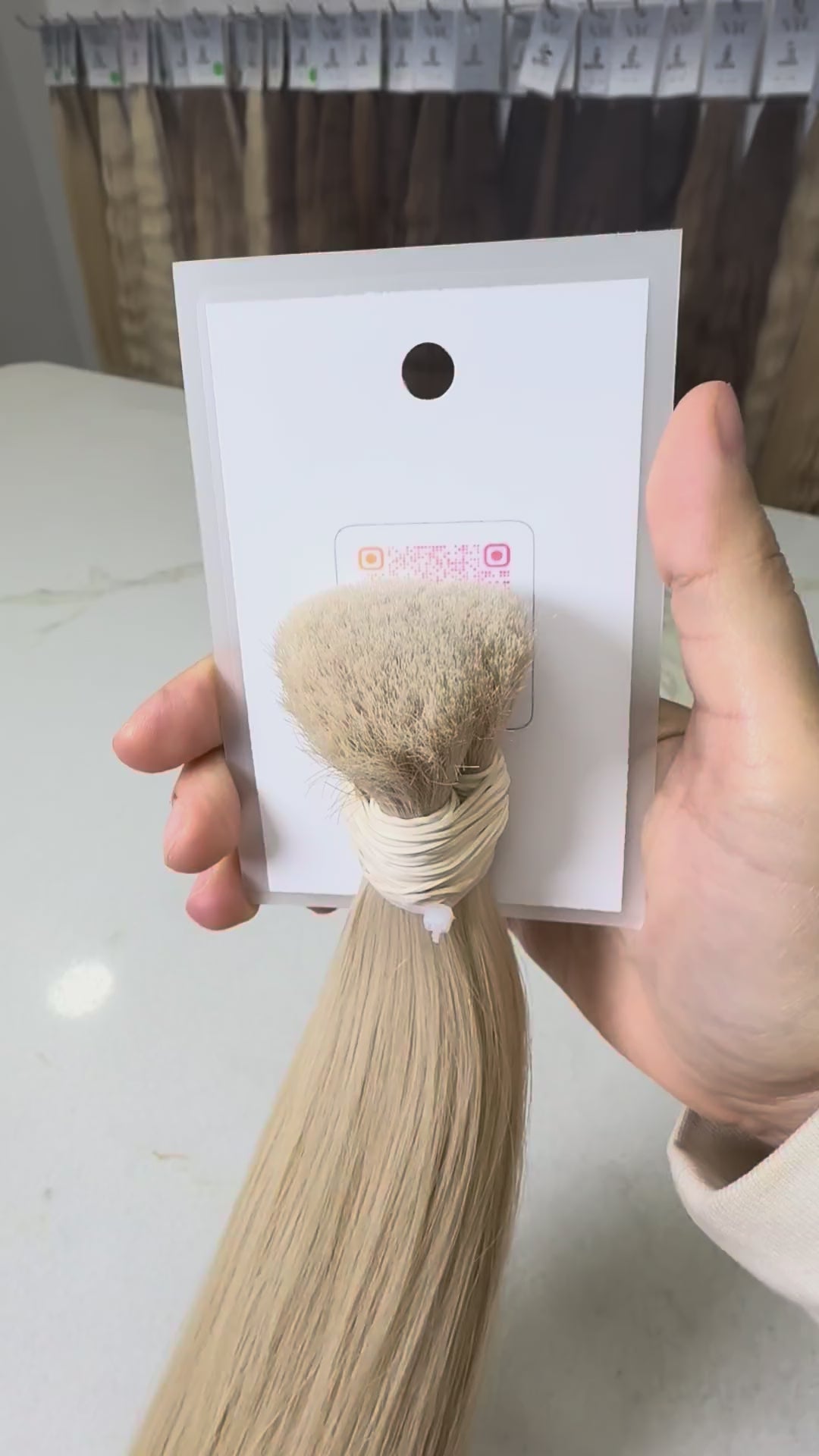 Blonde hair extensions with a label on a white surface.